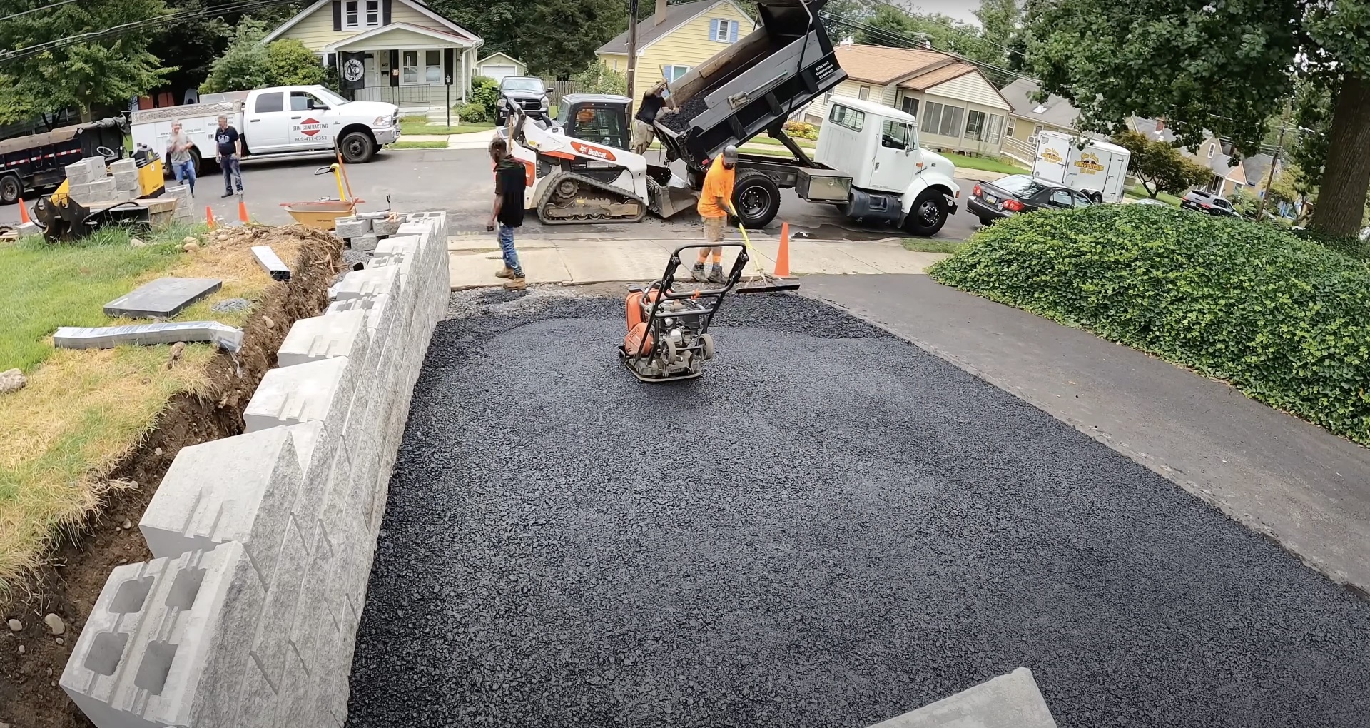 Professional asphalt driveway installation with concrete curbing and drainage